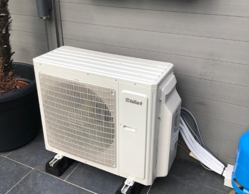 Buitenunit van een airco geplaatst op tegels