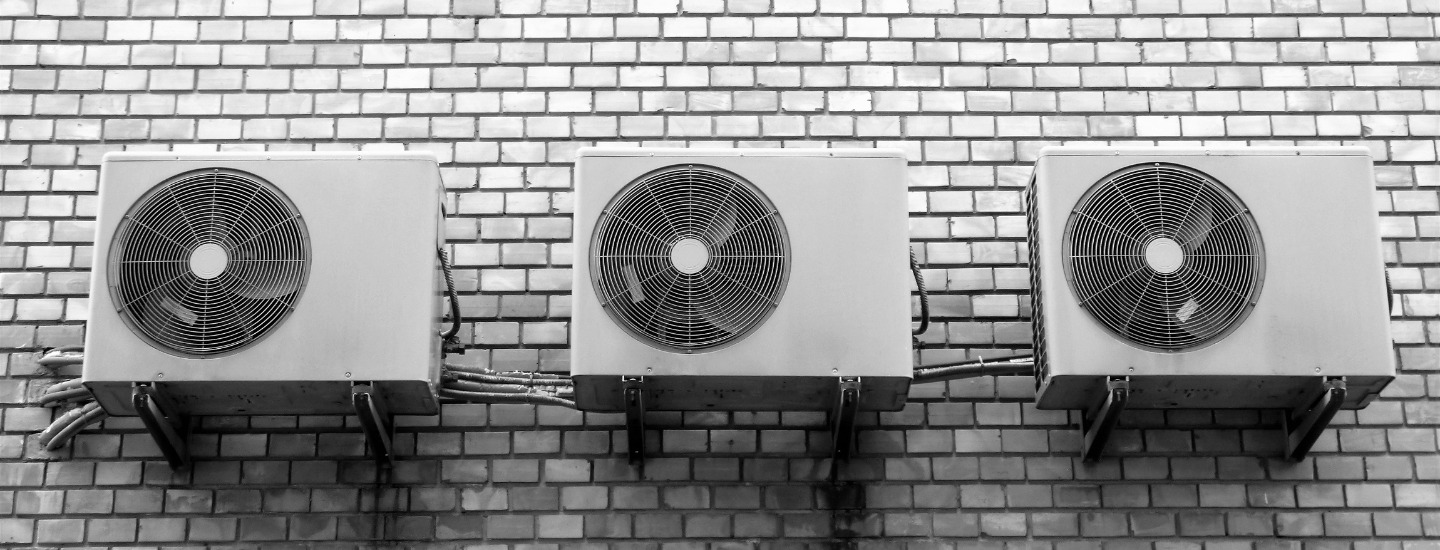 Drie buitenunits van airco's naast elkaar aan een gevel