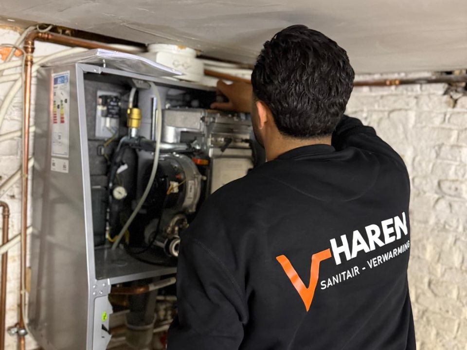 Technicus werkt aan een geopende verwarmingsketel tijdens een onderhoudsbeurt