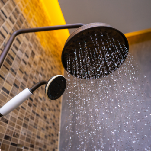 Douchekop boven een douche waarvan de afvoer traag wegloopt